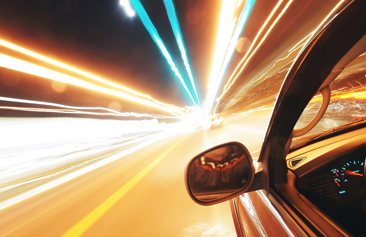 Len Sie ein Bild, das einen schnell fahrenden Rennwagen auf einer kurvigen Strecke in der Abenddämmerung zeigt, aufgenommen mit einer Kamera mit hoher Bildwiederholfrequenz